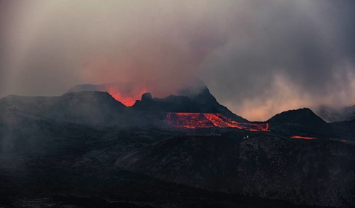 Erupting volcano with lava fountains and lava field