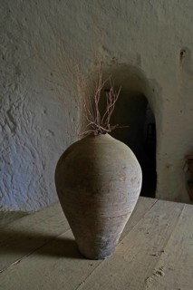 Old clay jug with bare branch in cave house