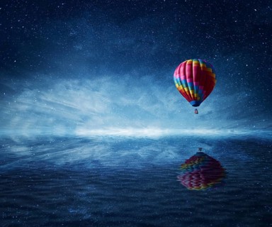 Hot air balloon flying over the a cold dark blue sea