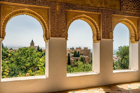 View of Nasrid Palaces through arches of Generalife Palace in Alhambra in Granada