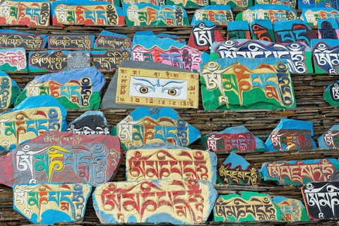 Huge piled up mountain of mani stones with Tibetan writing at a Tibetan monastery in the grasslands of Tagong