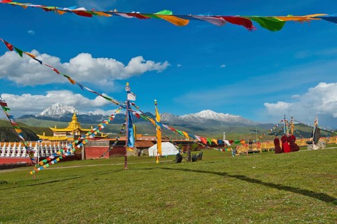 Golden roofs and chorten of a Tibetan monastery in the grassland of Tagong in front of Mount Zhara Lhatse