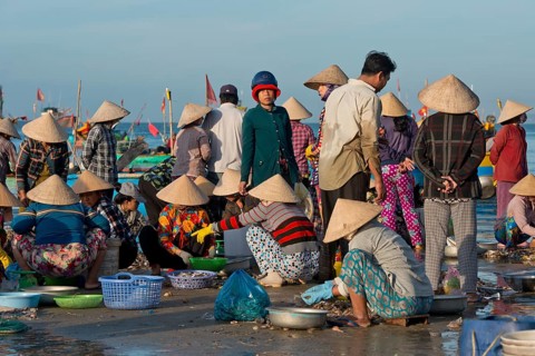 Women with straw hats on the beach with freshly caught fish and seafood