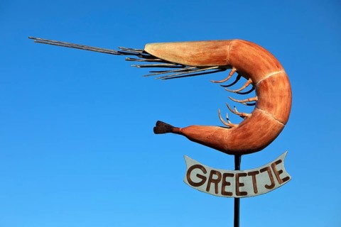 The sculpture of the North Sea crab Greetje at the fishing harbour against a blue sky
