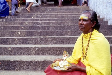 Elderly male Hindu beggar sitting on the steps of Dhandayuthapani temple at Palani near Coimbatore