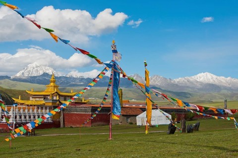 Golden roofs and chorten of a Tibetan monastery in the grassland of Tagong in front of Mount Zhara Lhatse