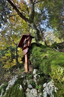 Memorial cross in autumnal mountain forest