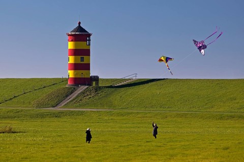 Girls flying kites in front of the Pilsum lighthouse