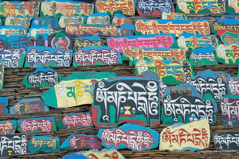 Huge piled up mountain of mani stones with Tibetan writing at a Tibetan monastery in the grasslands of Tagong