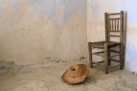 Traditional Spanish chair with straw hat in old house