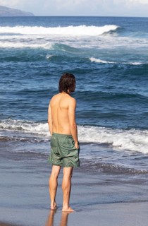 Young man standing in the sea on the beach of Praia de Santa Barbara
