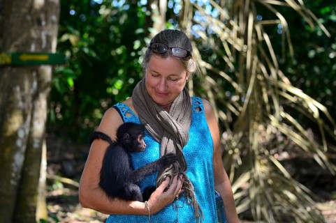 Tourist cuddles with a young peruvian spider monkeys