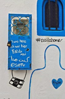 Graffiti painted windows on white wall in artist town Assila