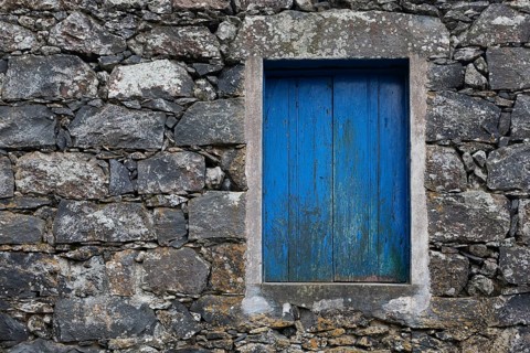 Residential house with stone facade and blue closed window in Rocha da Relva
