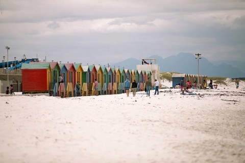 Holidaymakers in front of colourful beach huts