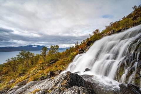Waterfall with view of lake Akkajaure and mountain range Akka