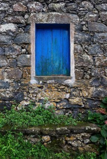 Residential house with stone facade and blue closed window in Rocha da Relva
