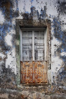 Weathered house facade with old closed window in Porto Formoso
