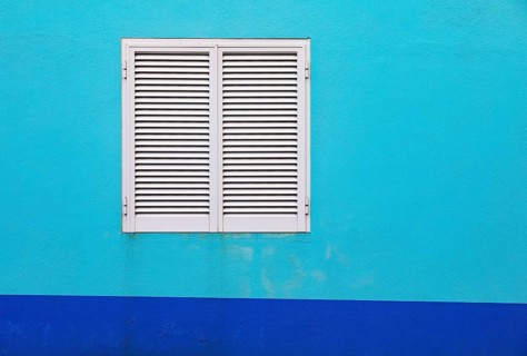 Light blue house facade with closed white shutters