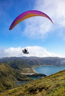 paraglider in flight over the crater lake Lagoa do Fogo