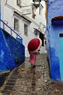 Woman with red umbrella in alleys of Chefchaouen