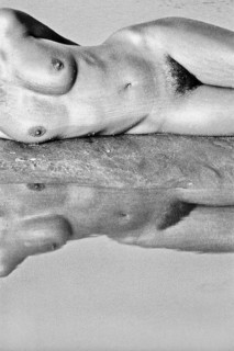 Nude photo of a lying woman at the water with reflection