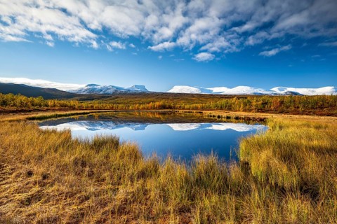 Mountain group Lapporten and snowy mountains of Abisko National Park reflected in small pond