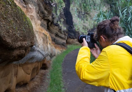 Hiker photographs eroded sand and lava rock on the path to Rocha da Relva