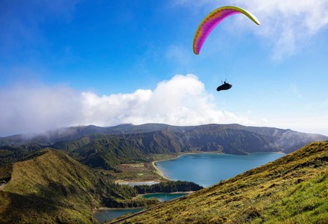 paraglider in flight over the crater lake Lagoa do Fogo