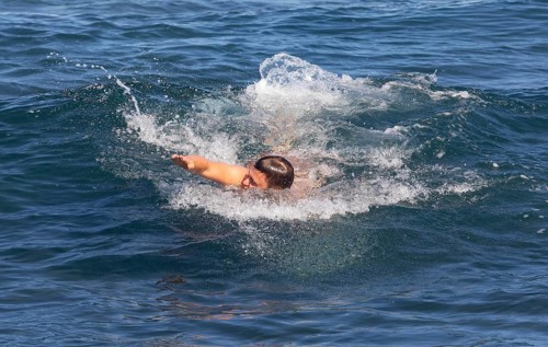 Young man swimming in the sea at the beach of Praia de Santa Barbara