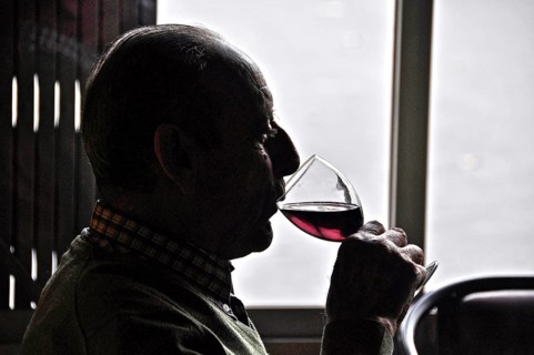 Old man drinking red wine against the light