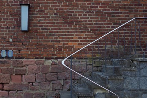 Stairs with railing in front of red brick wall