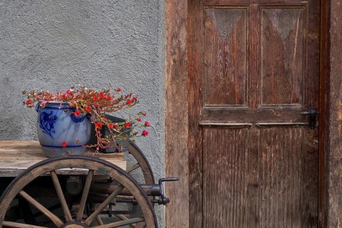 Still life with clay pot and wooden wagon in front of wooden door
