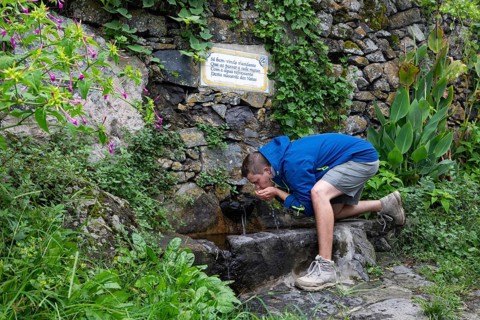 Hiker drinking at the fountain to the path to Rocha da Relva