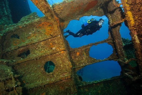 Diver looking into interior of sunken ship decaying rusting shipwreck Elviscot