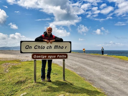 Tourist leaning against welcome sign in Irish