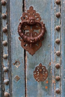 Ornate iron door knocker on mint green wooden door