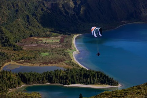 paraglider in flight over the crater lake Lagoa do Fogo