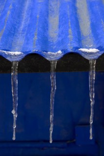 Three icicles on roof of blue corrugated iron