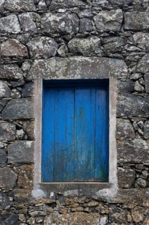 Residential house with stone facade and blue closed window in Rocha da Relva