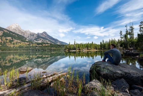 Young man sitting on a stone by a lake
