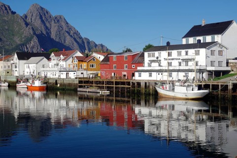 Fishing boats and houses reflected in the calm waters of a harbour