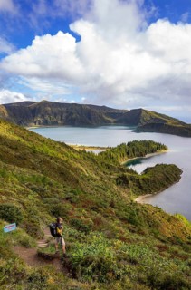 Hiker at the crater rim with view to the crater lake Lagoa do Fogo