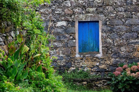 Residential house with stone facade and blue closed window in Rocha da Relva