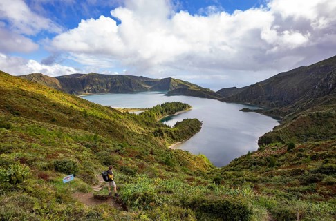 Hiker at the crater rim with view to the crater lake Lagoa do Fogo