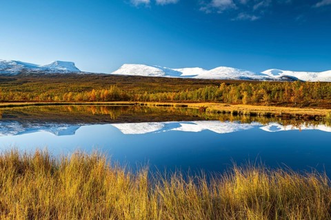 Mountain group Lapporten and snowy mountains of Abisko National Park reflected in small pond