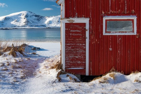 Red boathouse in winter Scandinavian landscape