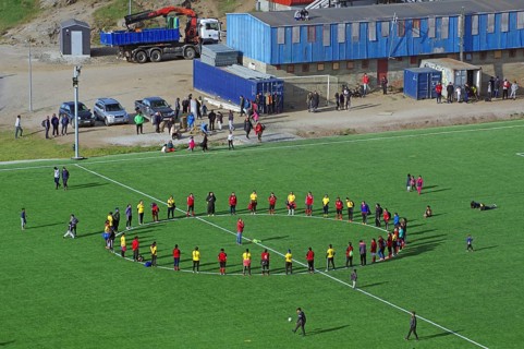 Footballers stand on grass pitch in the circle