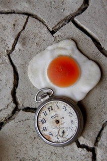 Handless pocket watch with fried egg on dried clay floor