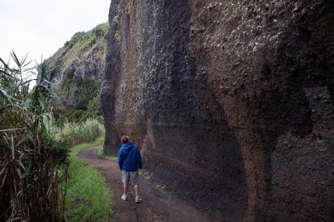 Hikers on the path to Rocha da Relva past eroded lava rocks